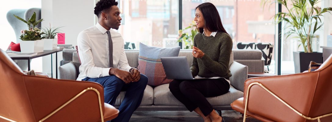 Businesswoman Interviewing Male Job Candidate In Seating Area Of Modern Office “Tell me about yourself”