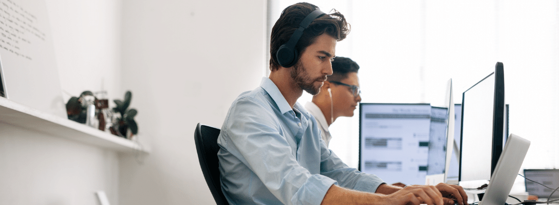 IP Software development blog header man in shirt wearing headphones working on a computer software development