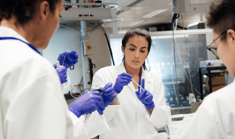 three people in lab coats women stem