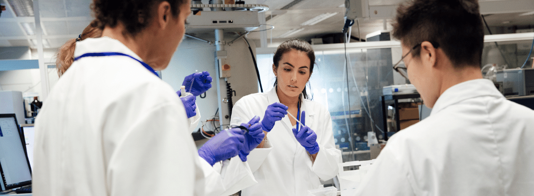 three people in lab coats women stem