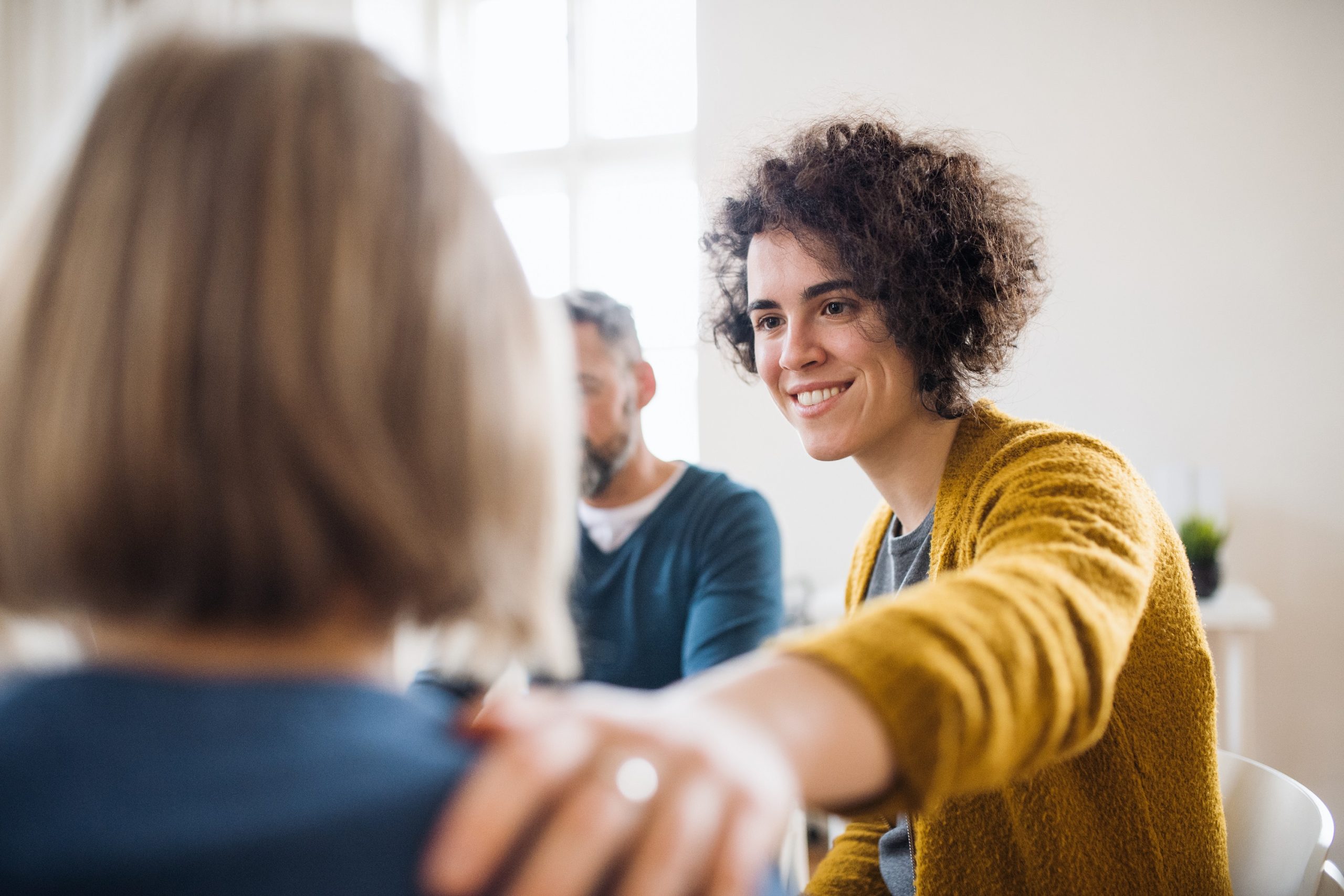 Men and women sitting in a circle during group therapy, supporting each other. 5 creative ways to reduce stress in the office and for remote teams