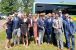 A group photo stood in front of a bus. Everyone is dressed very smart.