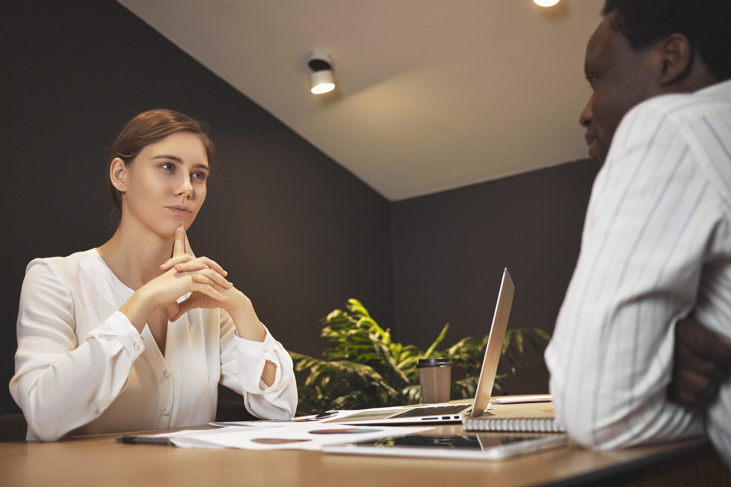Confident young European female in white blouse conducting job i Why did you leave your last job? How to answer this tricky interview question