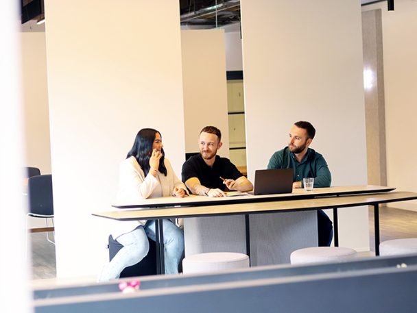 Two men and a woman sat at a desk working